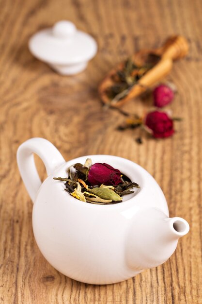 Green tea with fruits spices rose petals in white teapot