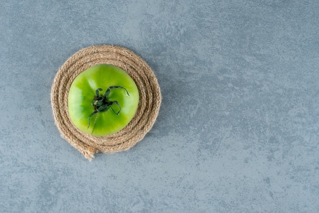 Pomodoro verde con corda su marmo.