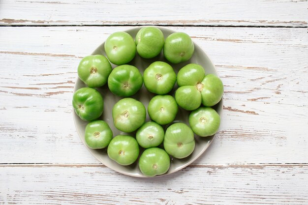 Green tomatoes, Pickles on white wooden table with green and red and chili peppers, fennel, salt, black peppercorns, garlic, pea, close up, healthy concept, top view, flat lay