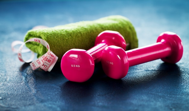 Free photo green towel, with a tape measure and some pink weights