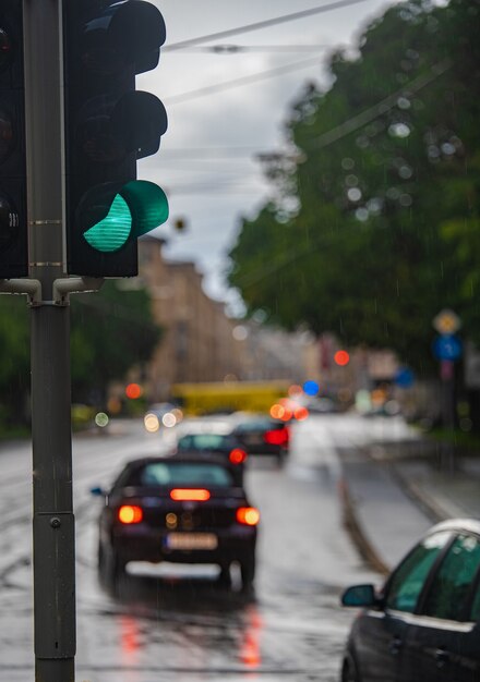 Зеленый светофор во время дождя, автомобили проезжают мимо