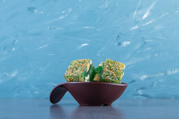 Green Turkish delights in a bowl, on the marble background.