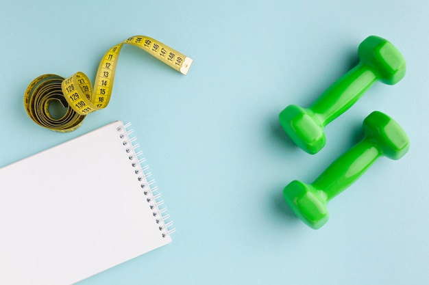 Green weights and notebook on blue background