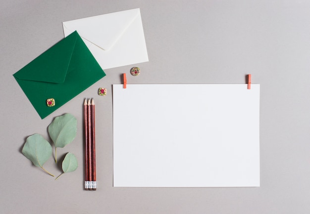 Green and white envelope; pencils and blank paper on gray backdrop