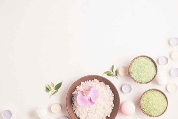 Green and white herbal sea salt with many small candles over white backdrop