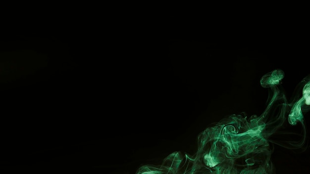 Green wispy smoke on the corner of black background with copy space