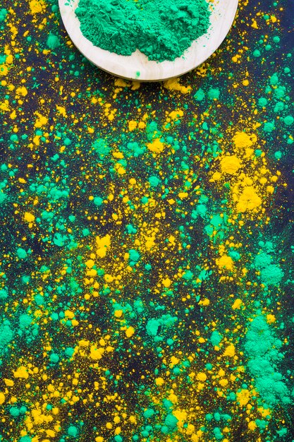 Green and yellow holi powder splatter on black background