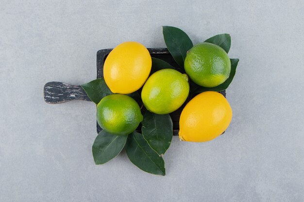 Green and yellow lemons on black cutting board