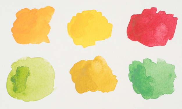 Green, yellow, orange and red blots of paints on white paper