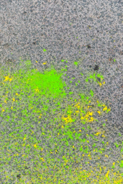 Macchie verdi e gialle di vernice su asfalto sgangherato