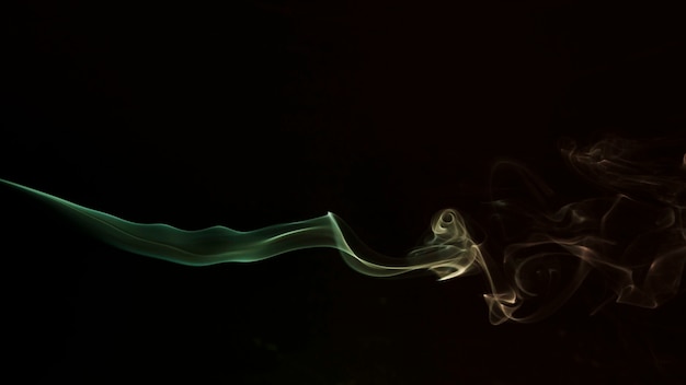 Green and yellow swirling smoke on black background