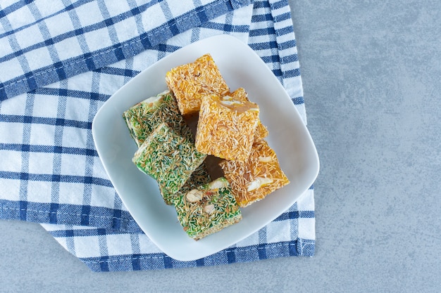 Free photo green and yellow turkish delights in bowl on the towel , on marble table.