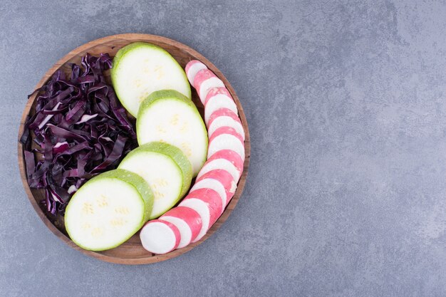 Green zucchini slices with chopped purple cabbage in a wooden platter