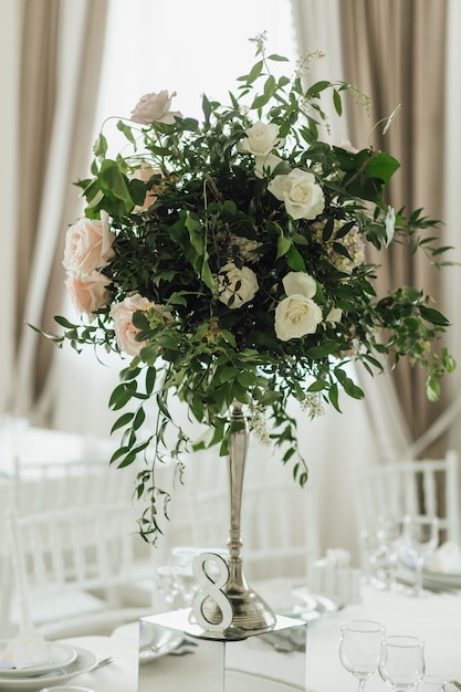 Greenery bouquet with roses stand on the feast table