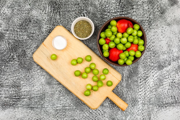 Greengages и персики с малой плиткой соли и высушенного протерли тимиан в коричневом шаре и разделочную доску на сером grunge, взгляд сверху.