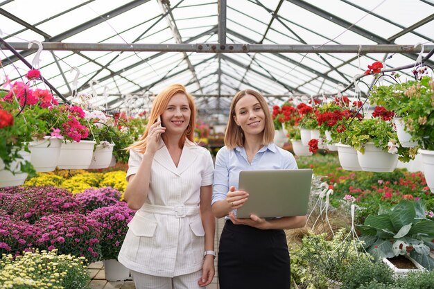 Greenhouse owner presenting flowers options to a potential customer retailer using laptop.