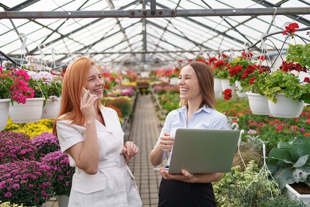 Greenhouse owner presenting flowers options to a potential customer retailer using laptop.