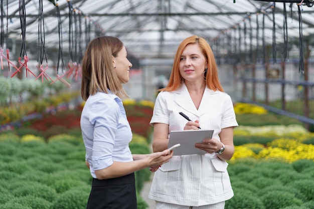 Greenhouse owner presenting flowers options to a potential customer retailer.