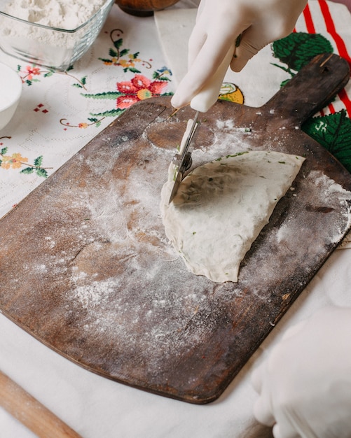 greenies qutab in process of making greens herbs dough cook on brown wood rustic desk