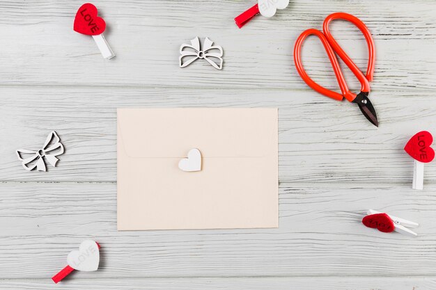 Greeting card surrounded with heart shape clip and scissor on wooden table