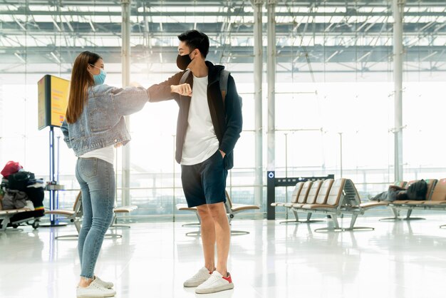인사하는 친구 여행자 캐주얼 옷은 팔꿈치와 발을 터치하여 인사하고 터미널 공항에서 새로운 삶의 방식으로 인사합니다.
