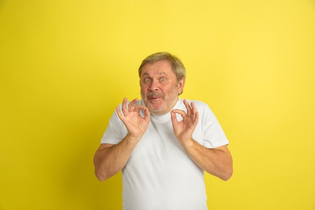 Greeting, inviting gesture. Caucasian man portrait isolated on yellow studio background. Beautiful male model in white shirt posing. Concept of human emotions, facial expression, sales, ad. Copyspace.