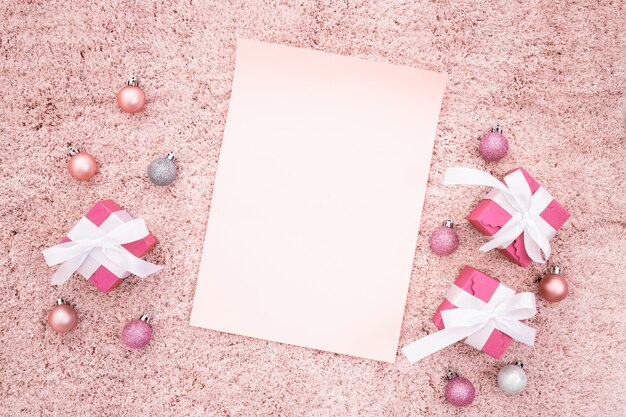 クリスマスギフトボックスとピンクの織り目加工のカーペットの上のボールでメモに挨拶