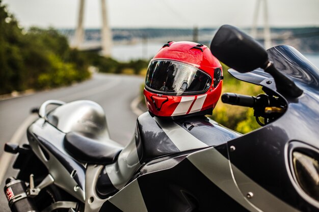 Серый черный мотоцикл и красный шлем.