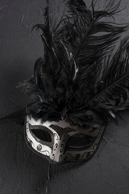 Grey carnival mask with feather on table