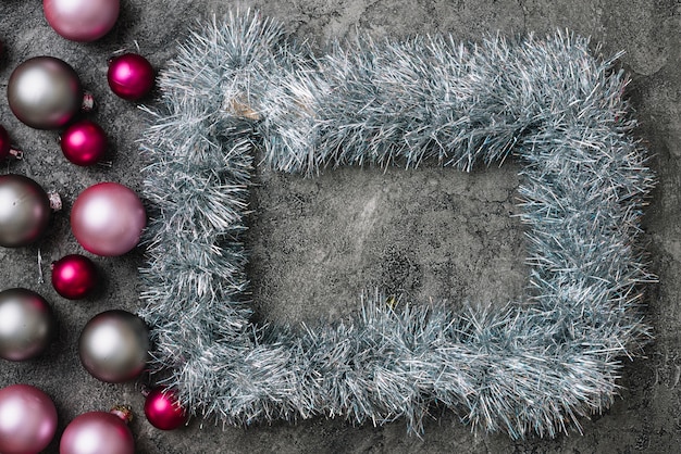 Free photo grey frame from tinsel with baubles