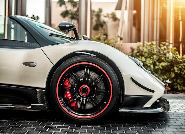 Grey, silver color sport car front side view with red wheels on the road.