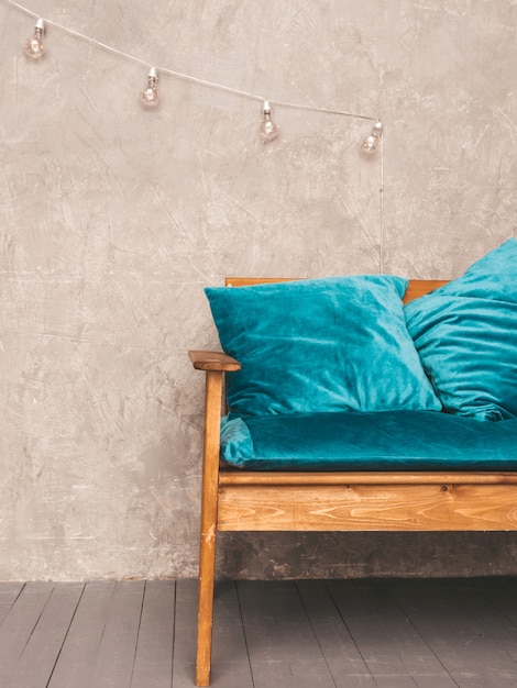 Grey wall interior with stylish upholstered blue and wooden modern sofa