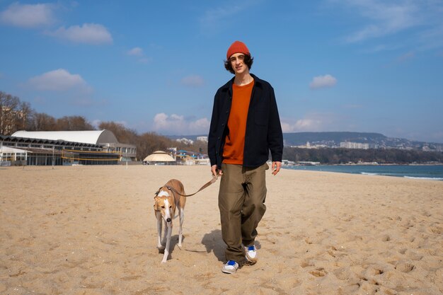 Greyhound dog with male owner at the beach