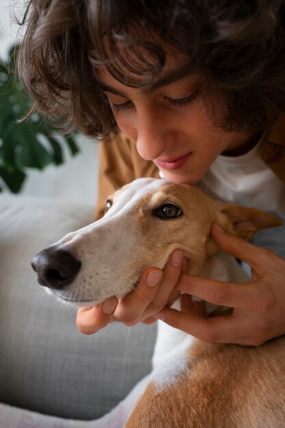 自宅のソファで男性の所有者と一緒にいるグレイハウンド犬