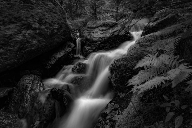 Greyscale long exposure shot of a small waterfall on the rocks