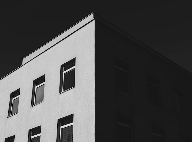 Greyscale low angle shot of a concrete building with a lot of windows under the dark sky