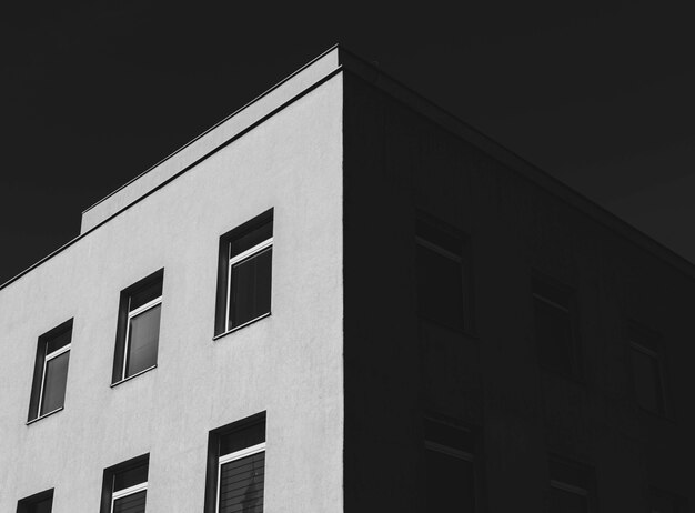 Снимок в оттенках серого бетонного здания с множеством окон под темным небом под низким углом