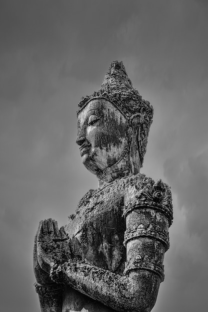 Greyscale shot of a Buddha statue under the dark sky