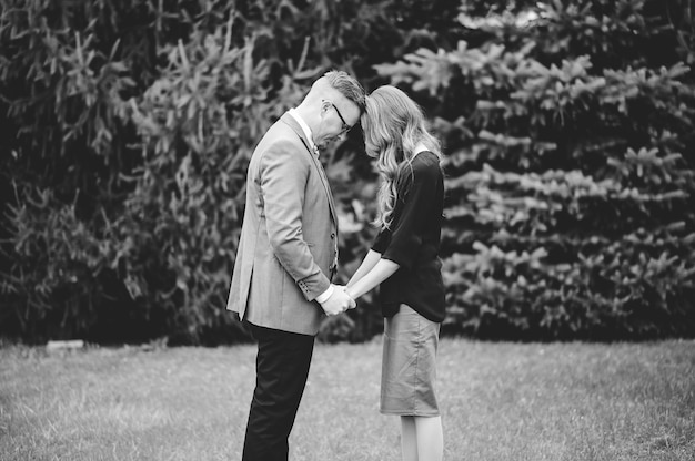 Greyscale shot of a couple holding the hands of each other and praying in a garden