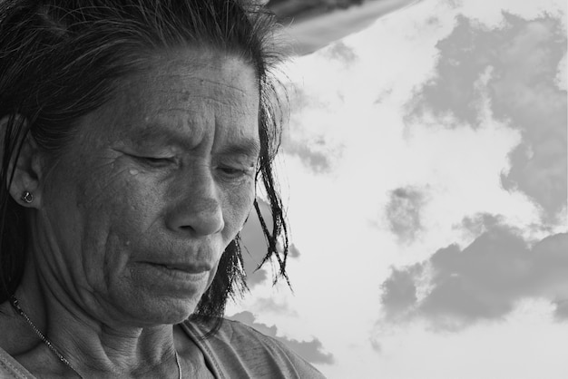 Greyscale shot of elderly female preparing food under an outside canopy in the Philippines