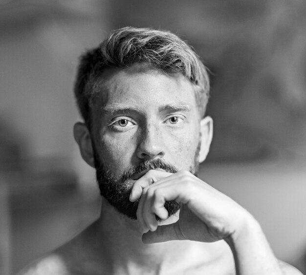 Greyscale shot of a handsome caucasian male with his hand on his chin