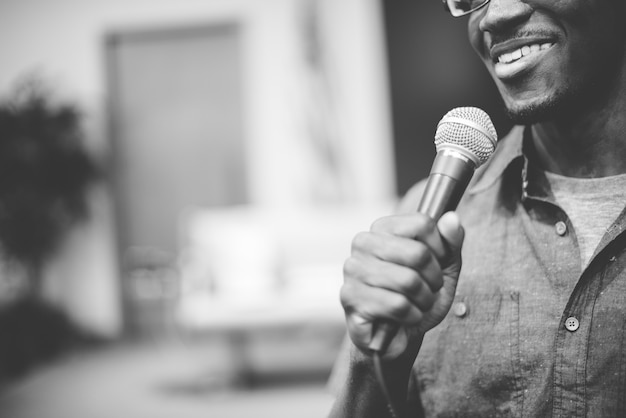 Greyscale shot of a happy man talking on the microphone