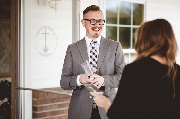 Greyscale shot of a suited man greeting and welcoming a female wearing a black shirt