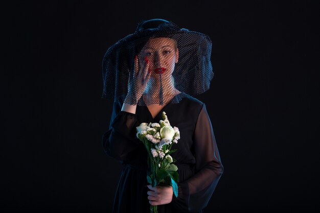 Grieving female dressed in all black with flowers on the black  sadness funeral death