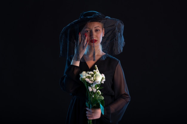 Grieving female dressed in all black with flowers on the black  sadness funeral death