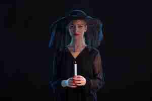 Бесплатное фото Скорбящая женщина, одетая в черное, с горящей свечой на черном столе, похороны печали смерти