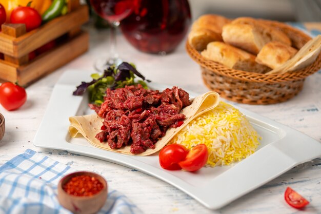 Grilled bbq beef meat slices, doner in lavash with green salad, tomatoes and rice garnish   