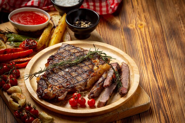 Grilled beef steak on the dark wooden surface.