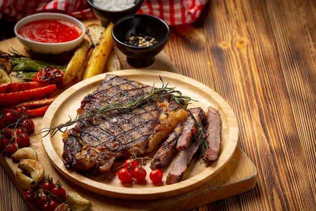 Grilled beef steak on the dark wooden surface.