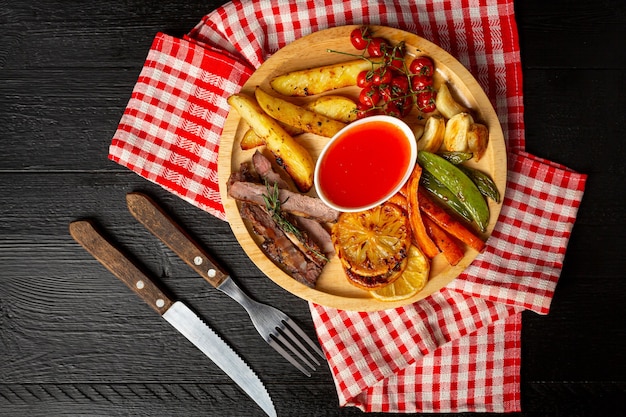 Grilled beef steak on the dark wooden surface.